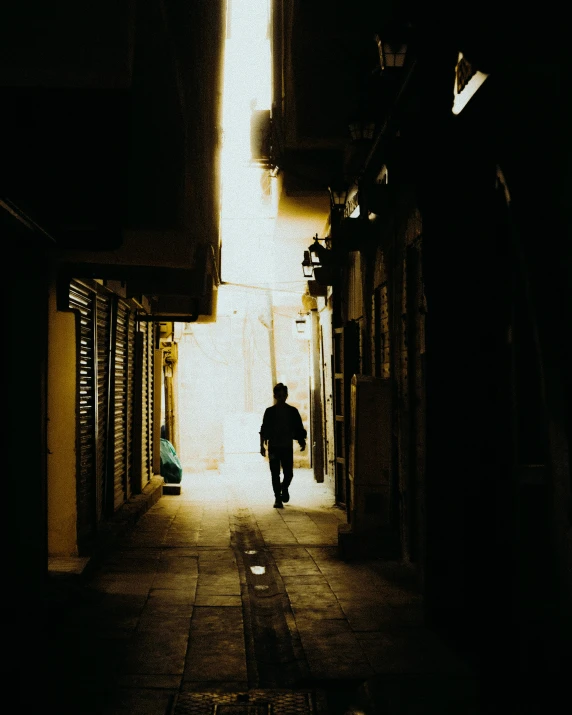 a man walking down a long narrow dark hallway