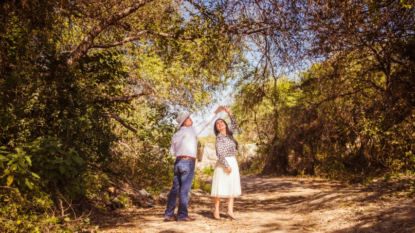 a couple standing under the trees on a path