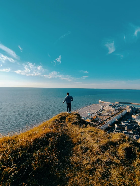 a man stands on a cliff near the ocean