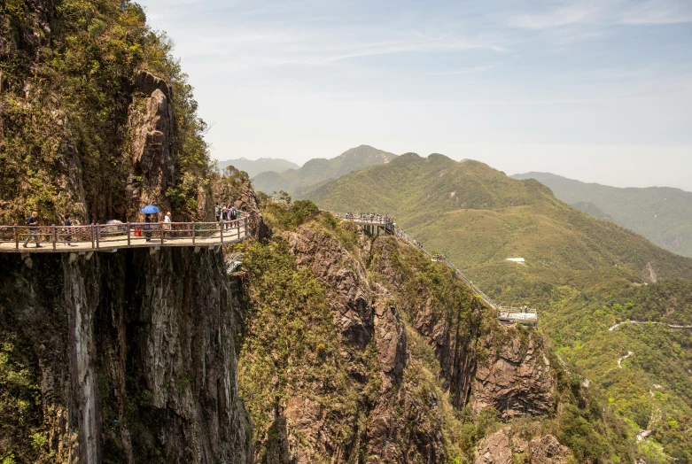 some people are standing on a bridge over a mountain