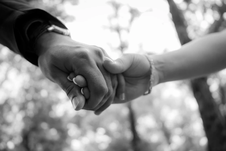 two people are holding hands in the woods