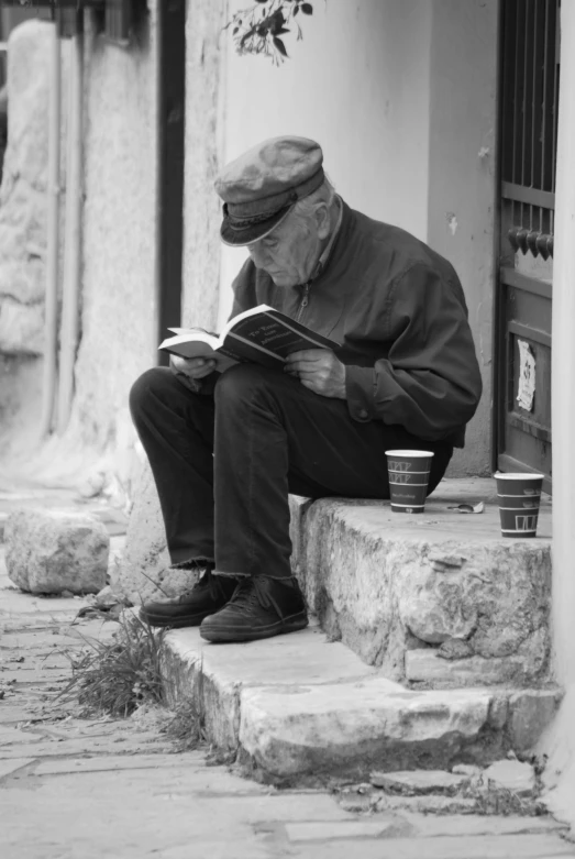 a man in a hat is reading a book on the steps