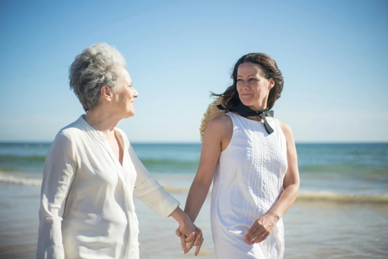 the woman is standing by the water holding hands with the old lady