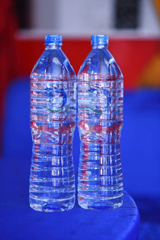 two plastic bottled water bottles, with red and white caps