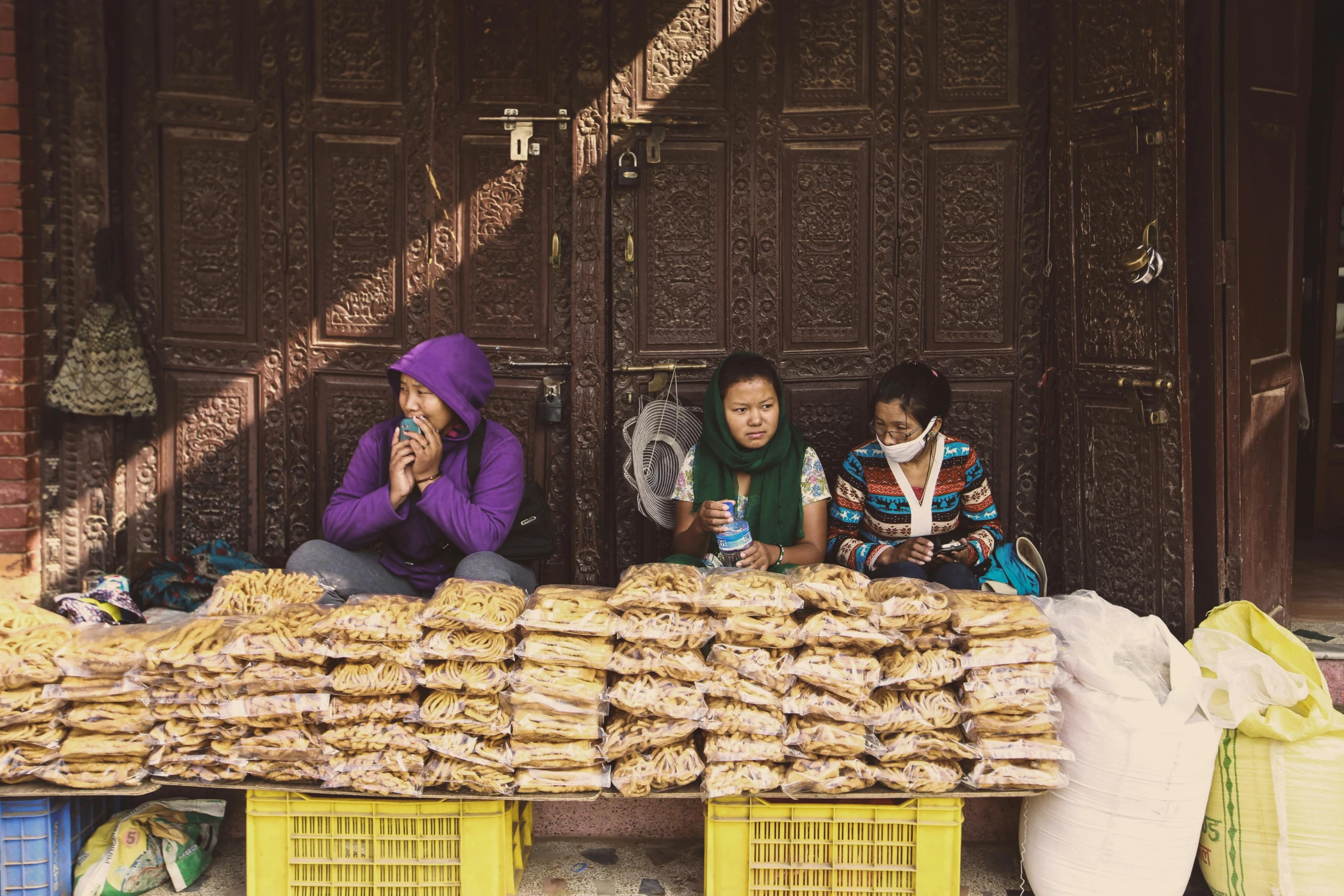 two women in purple clothing are outside with many bags