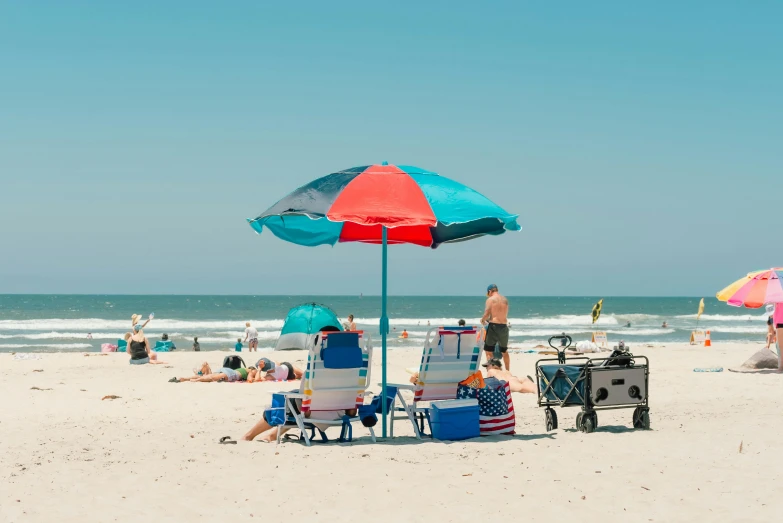 many people are enjoying a beach with chairs and an umbrella