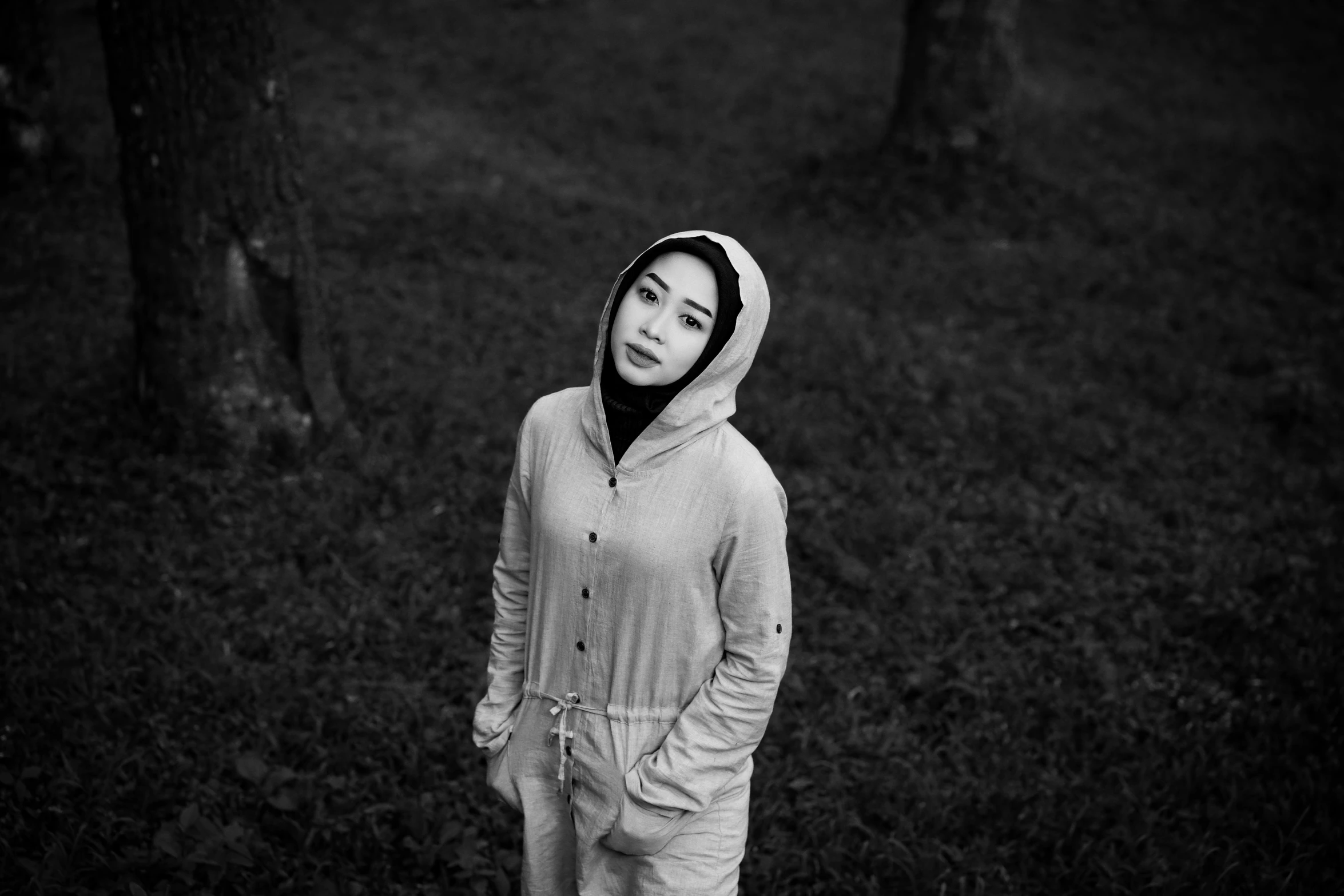 a girl standing by some trees while wearing all grey