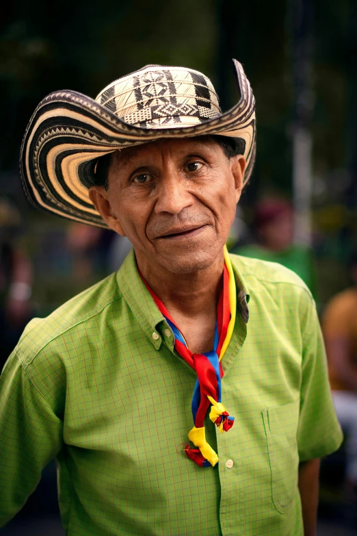 an older man in a hat has a colorful ribbon around his neck