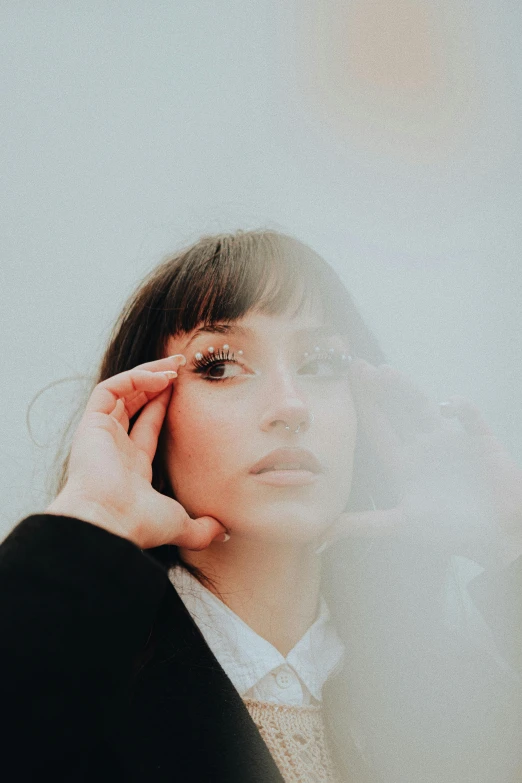 a woman in a business suit standing with her hand near her face