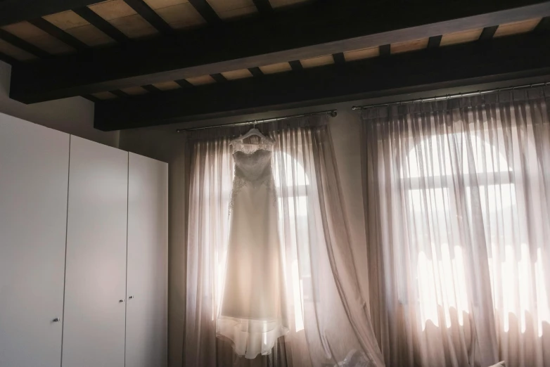 wedding dress hanging on the wall near a window