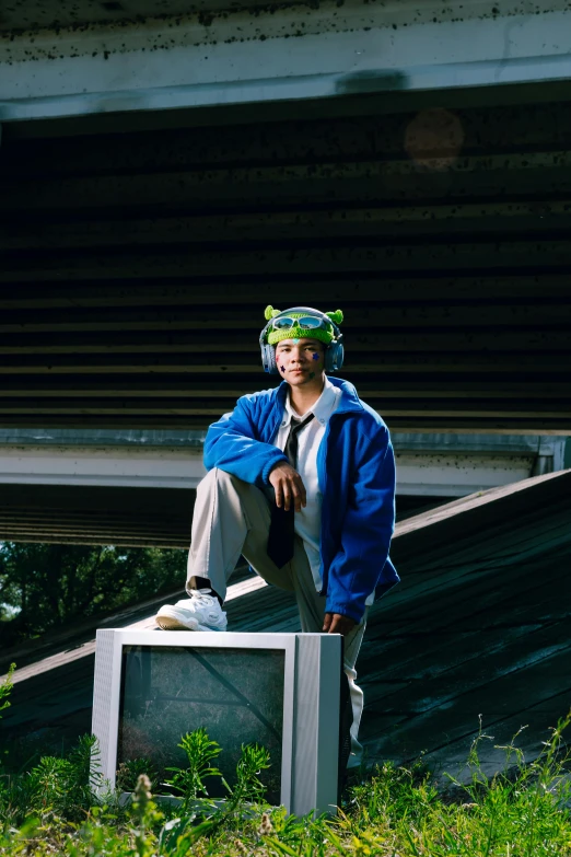 man in a blue jacket sitting on top of a tv