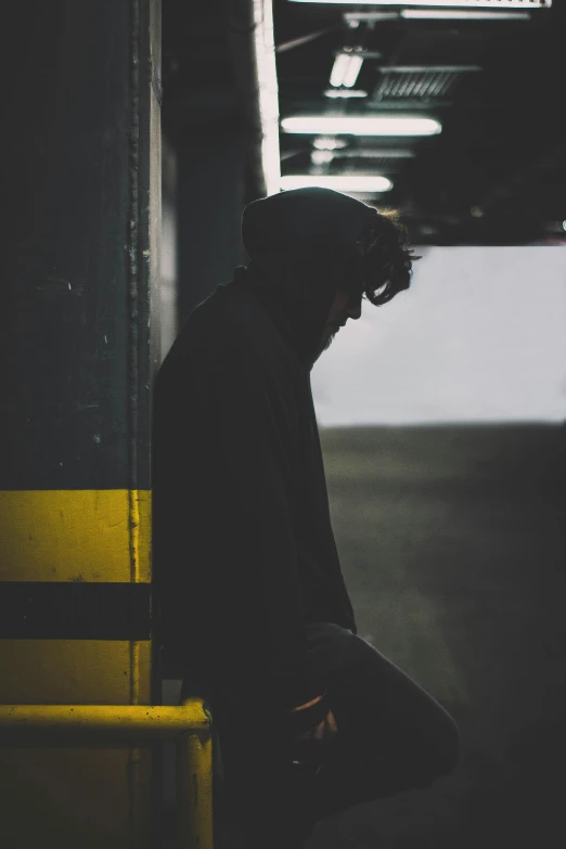 the man is waiting on the yellow bench for his train