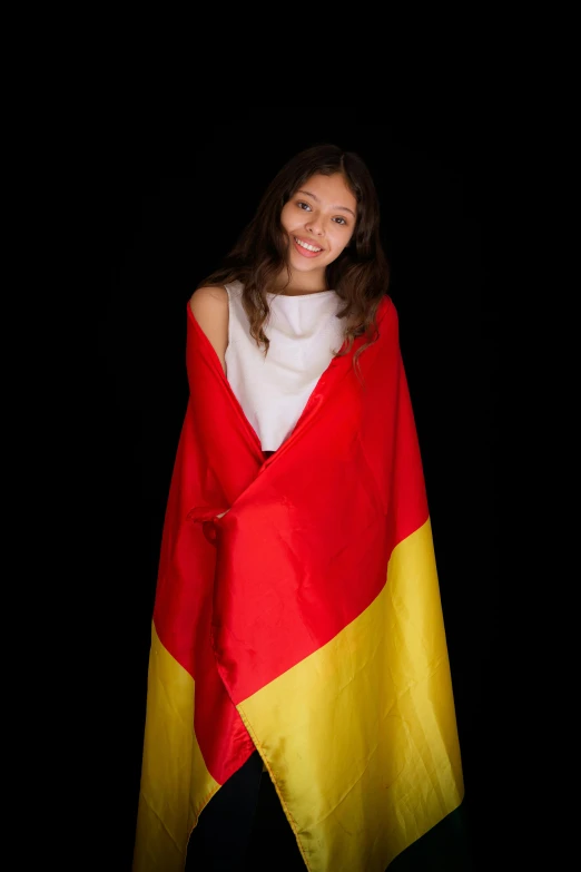 the girl is holding onto a red, yellow and black blanket