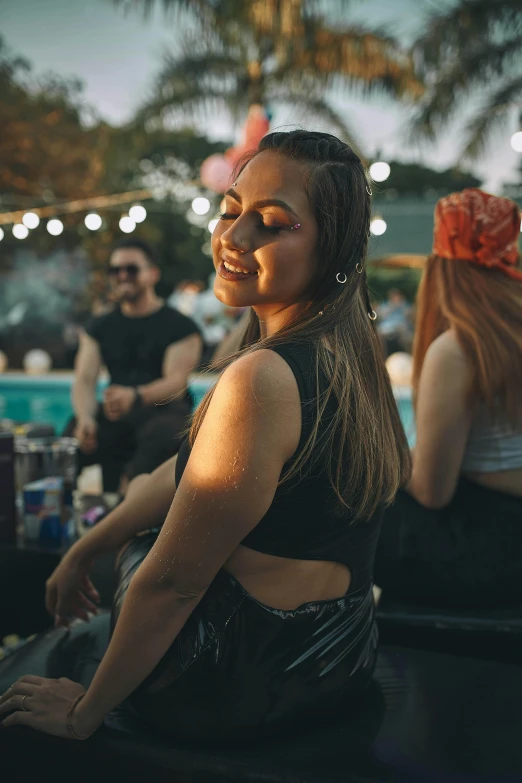 a woman sits near a pool with her face partially closed