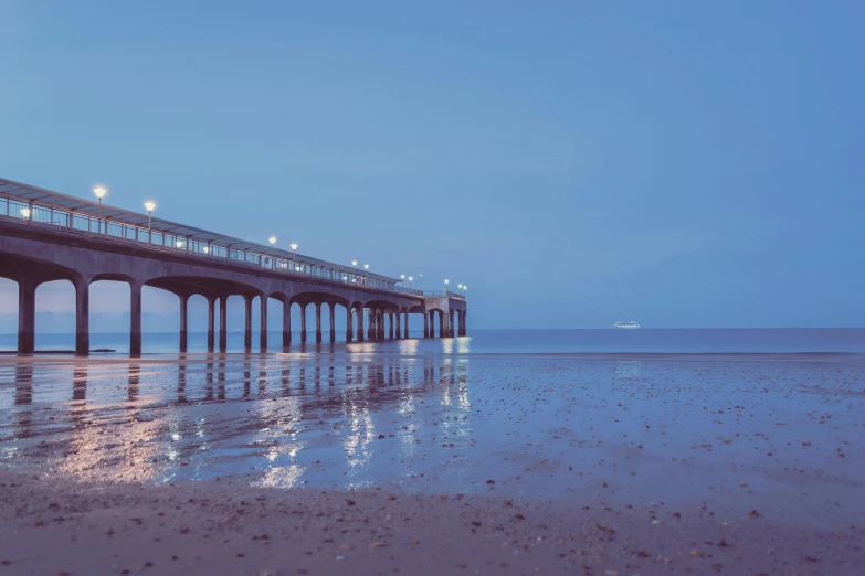 a long pier sits in the distance above some water