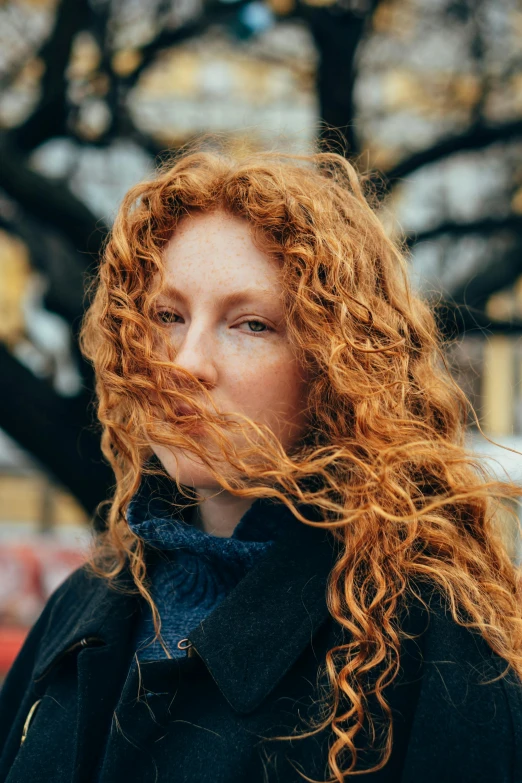 a woman with long red hair looks off to her side