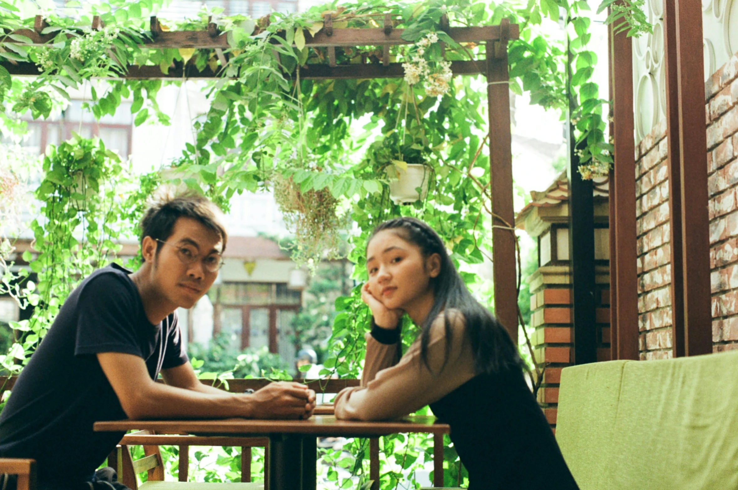 two people sit at an outdoor table on their phones