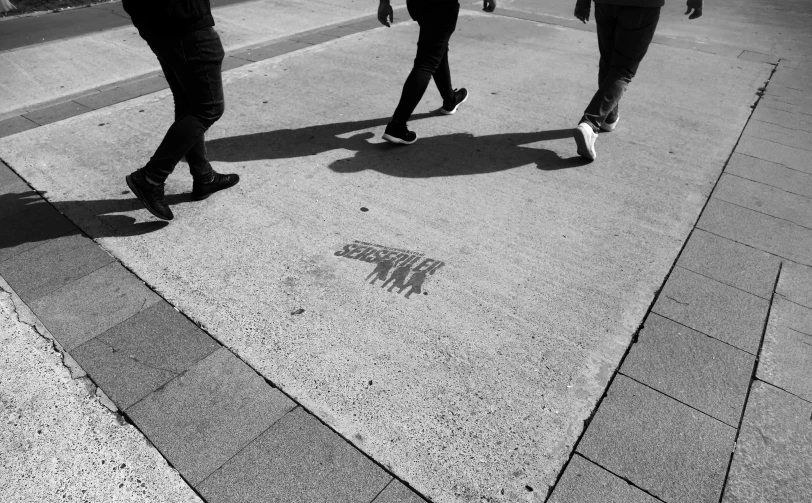 some people are walking on the sidewalk with skateboards