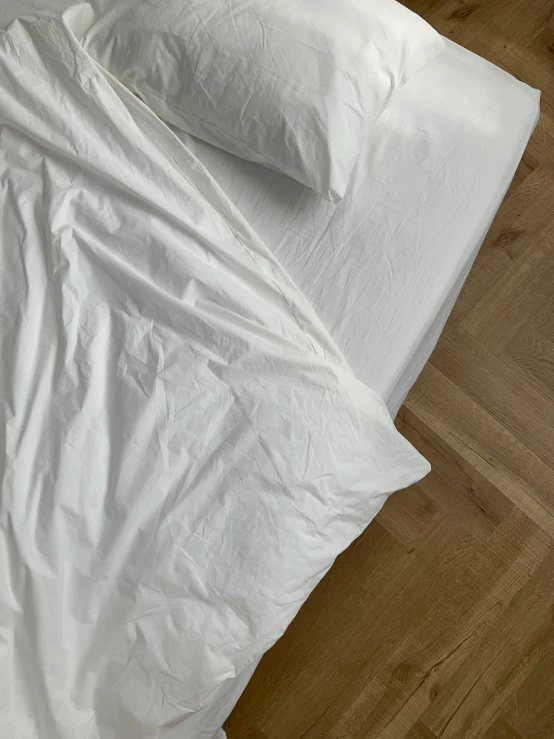 a white bed in a room next to a wood floor