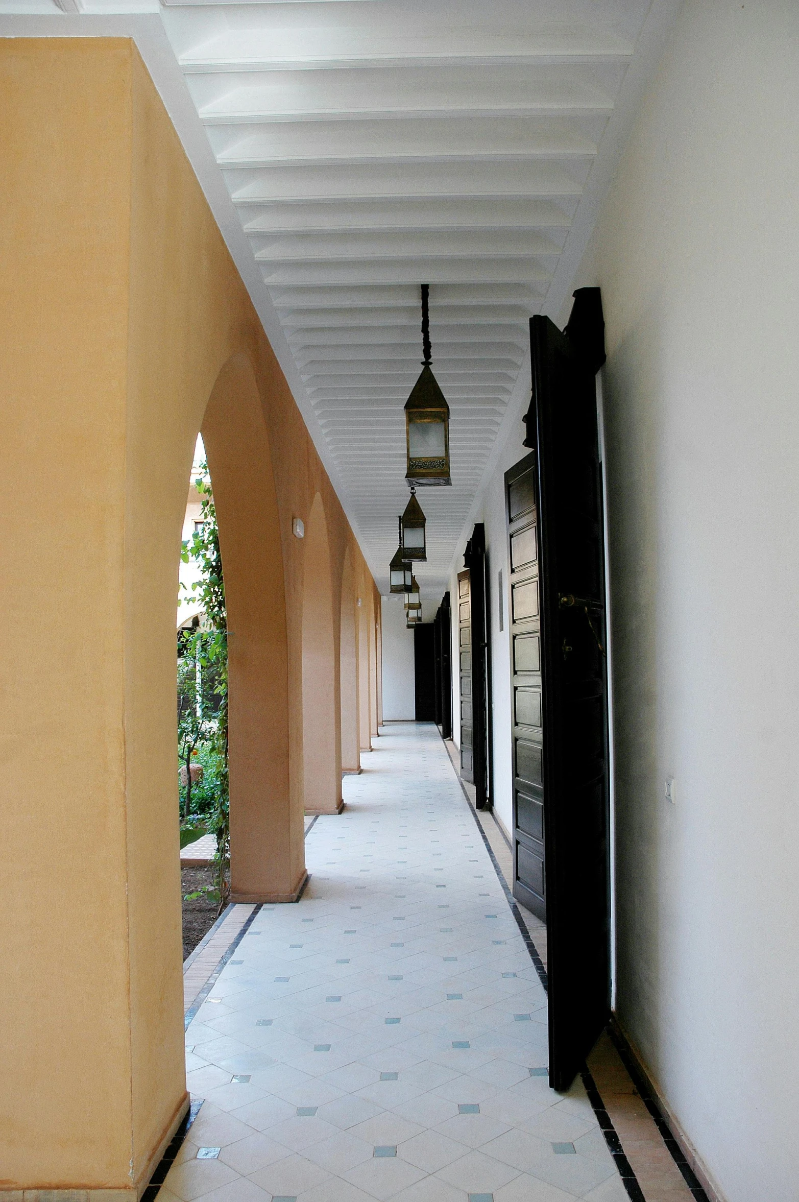 a corridor leading to a restaurant and rooms with lamps