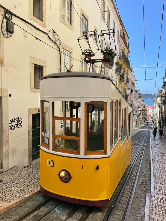 a very old cable car going down some narrow street