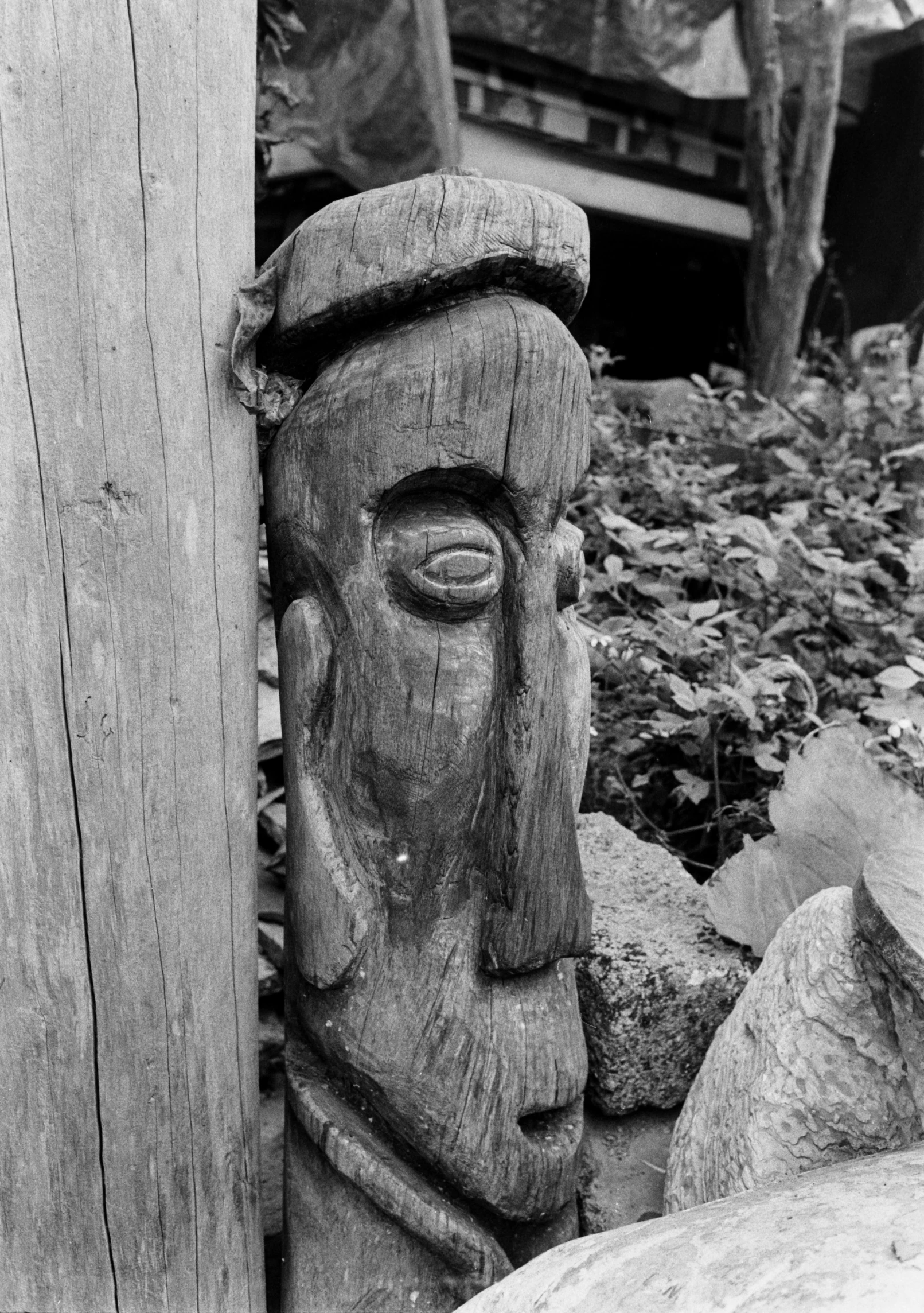 a wood carving sculpture sitting in the grass near rocks