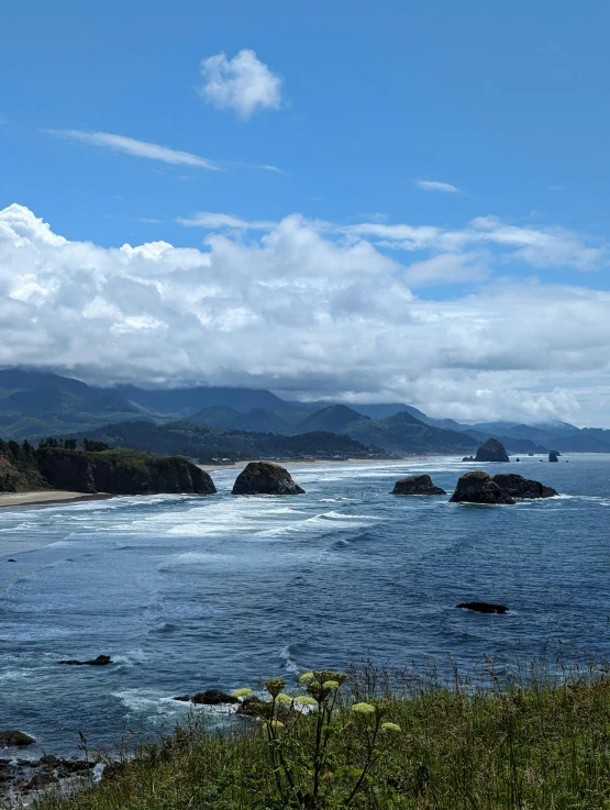 some rocks near the ocean water with mountains in the background