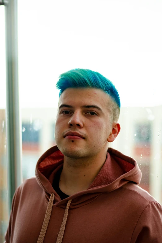 a man with a bright turquoise mohawk standing