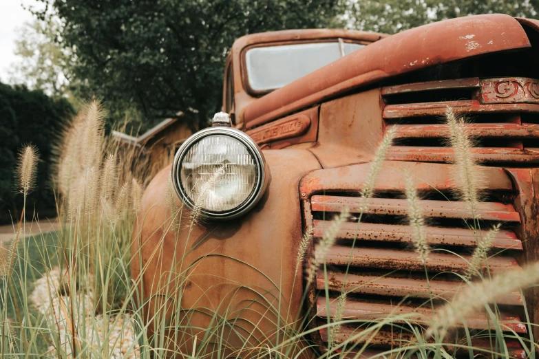 an old rusted out truck sitting in the grass