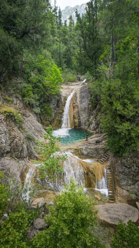 a waterfall running through the woods into a lake