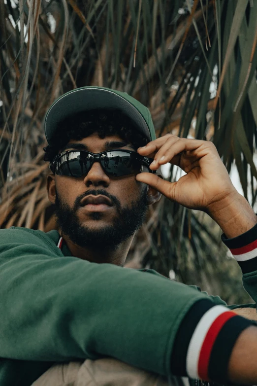 a man in a green jacket sitting on top of a palm tree