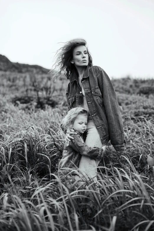 a woman holding onto a small child in the grass