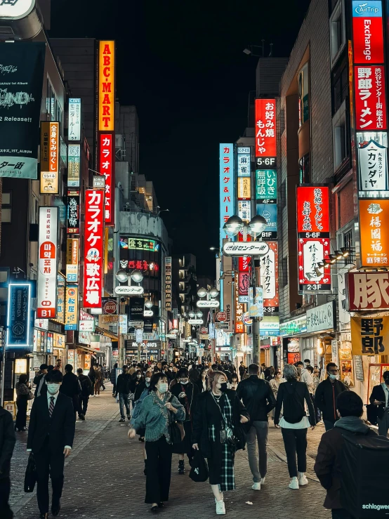 a crowded city street lined with lots of neon signs