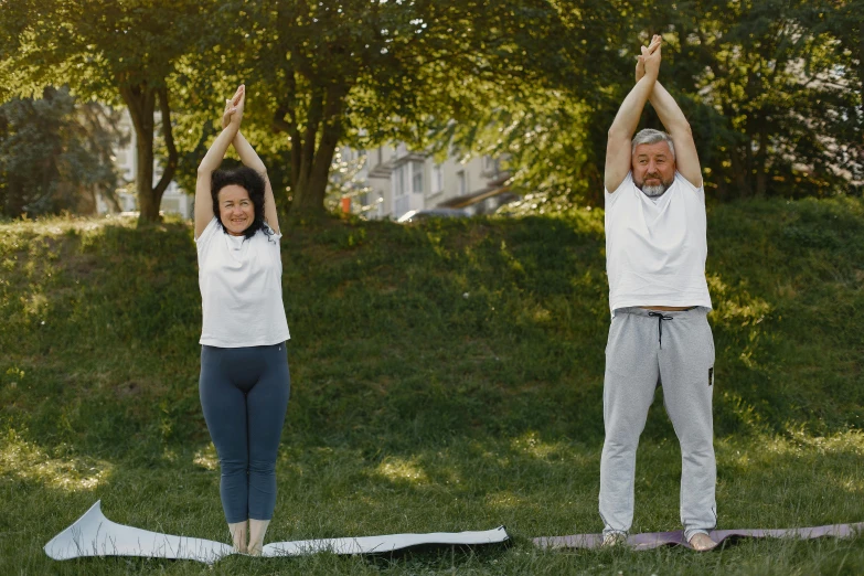 a man and a woman standing on yoga mats in a park