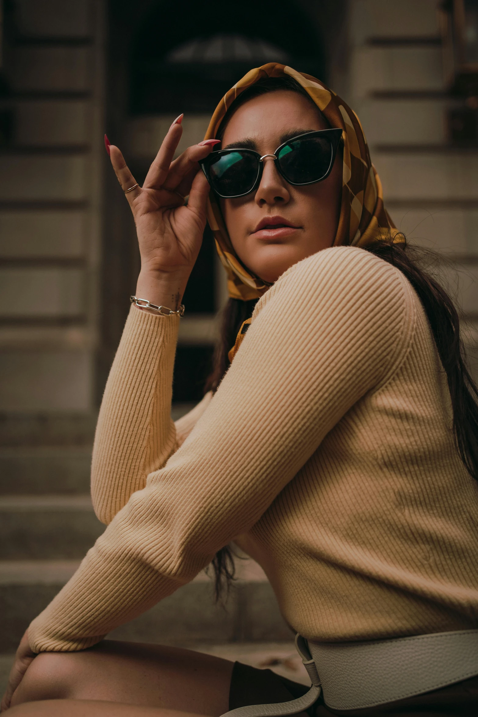 woman sitting with her hand on the face wearing green sunglasses