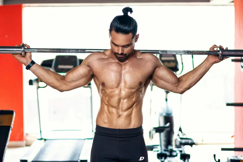 the man is standing in a gym holding a bar over his head