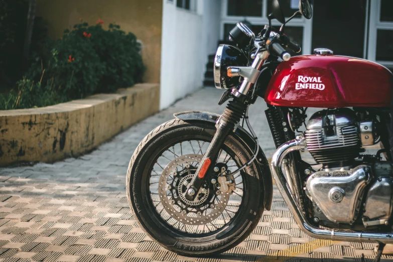 a royal enfield motorcycle parked on the sidewalk in front of a building