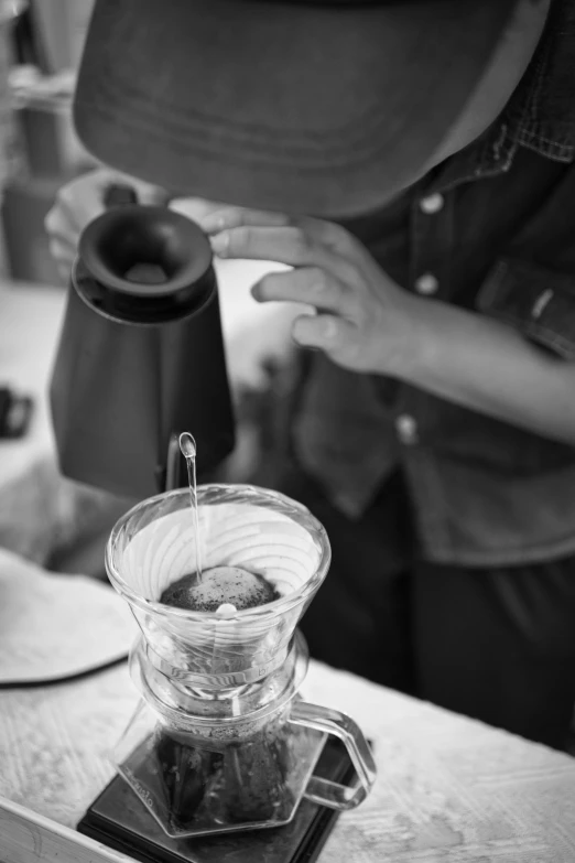 person pouring water into a clear pitcher