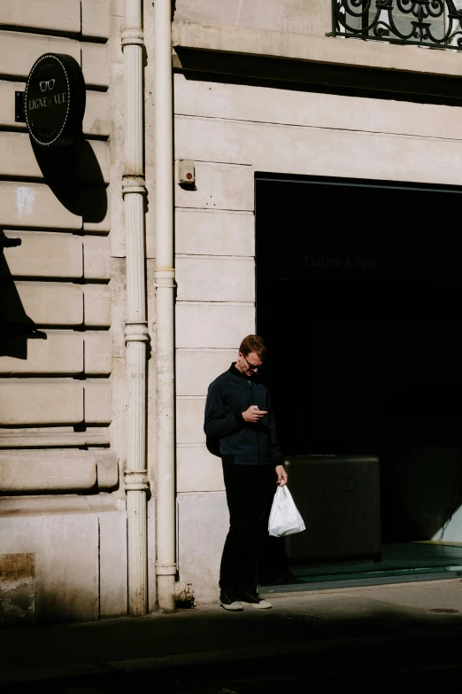 the man is walking past a building in his jacket