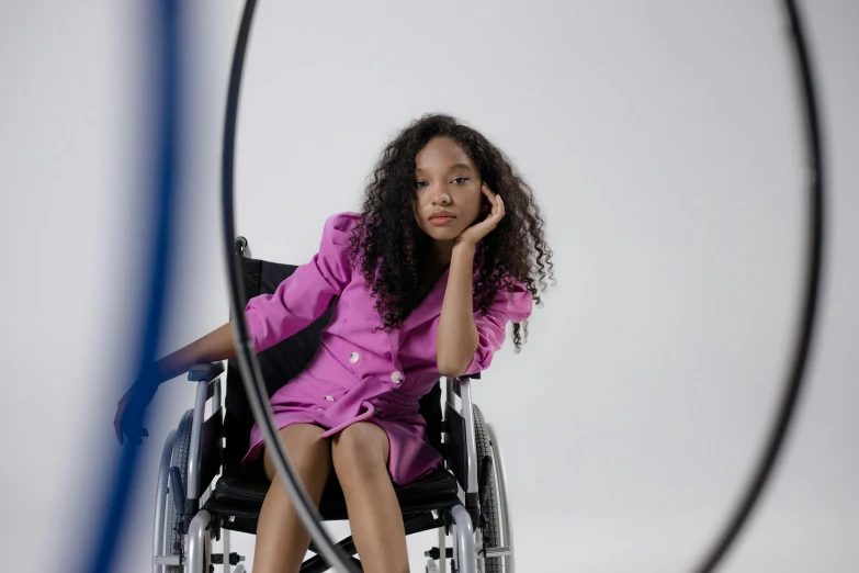 a woman in a wheelchair sitting down, with one foot on her chin