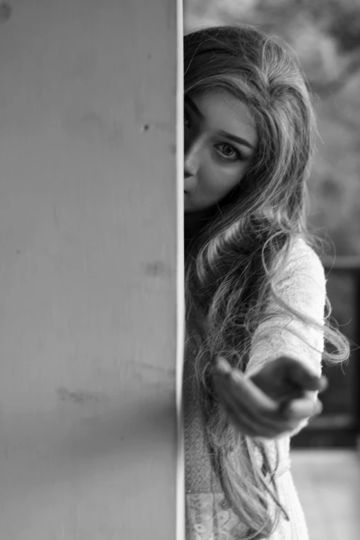 a woman with long hair leaning against a wall