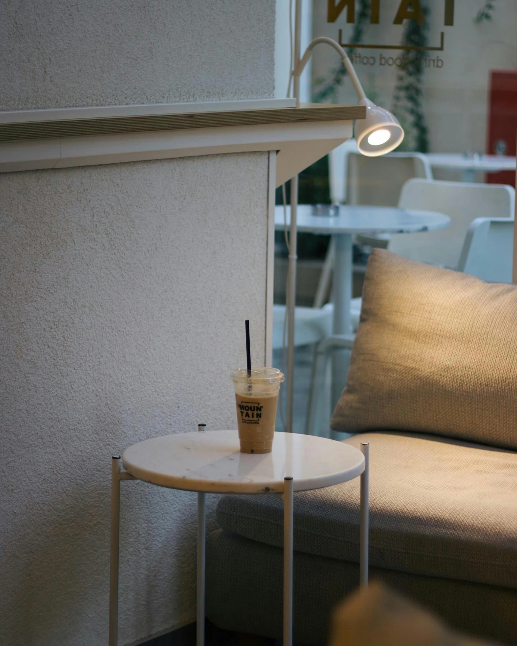 a coffee cup on a small table with a straw in it next to a couch