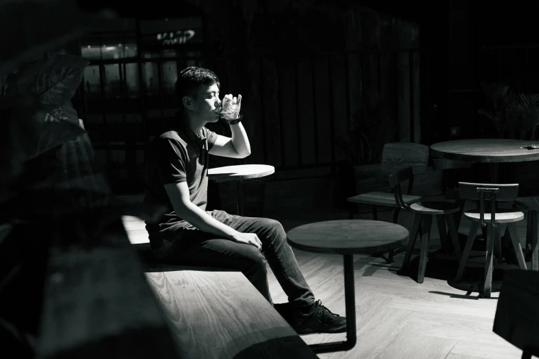 man drinking in a dark room with many stools