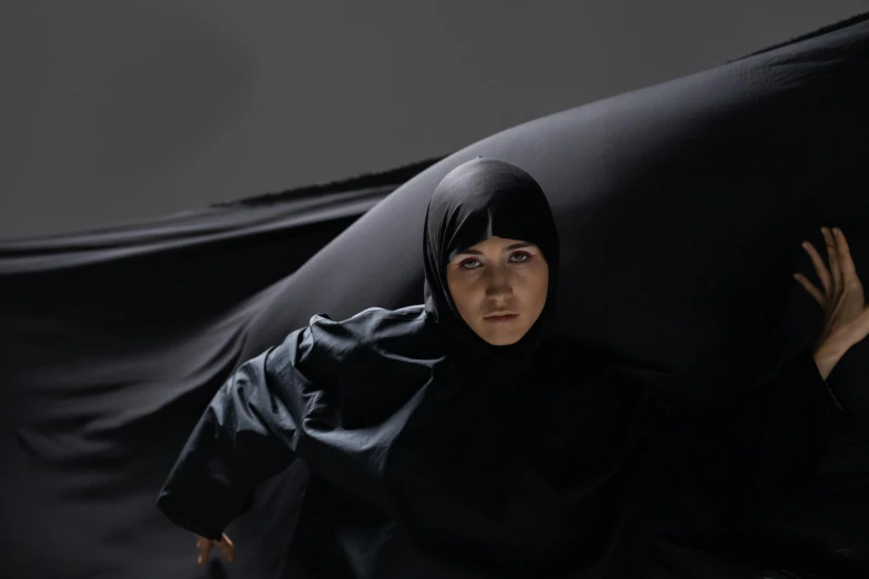 a woman in hijab sitting on a couch looking up