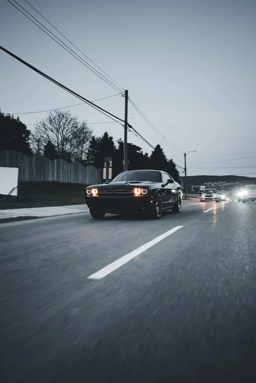 two cars driving on an empty road with their headlights on