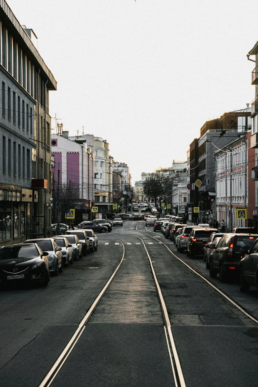 street lined with lots of parked cars and buildings