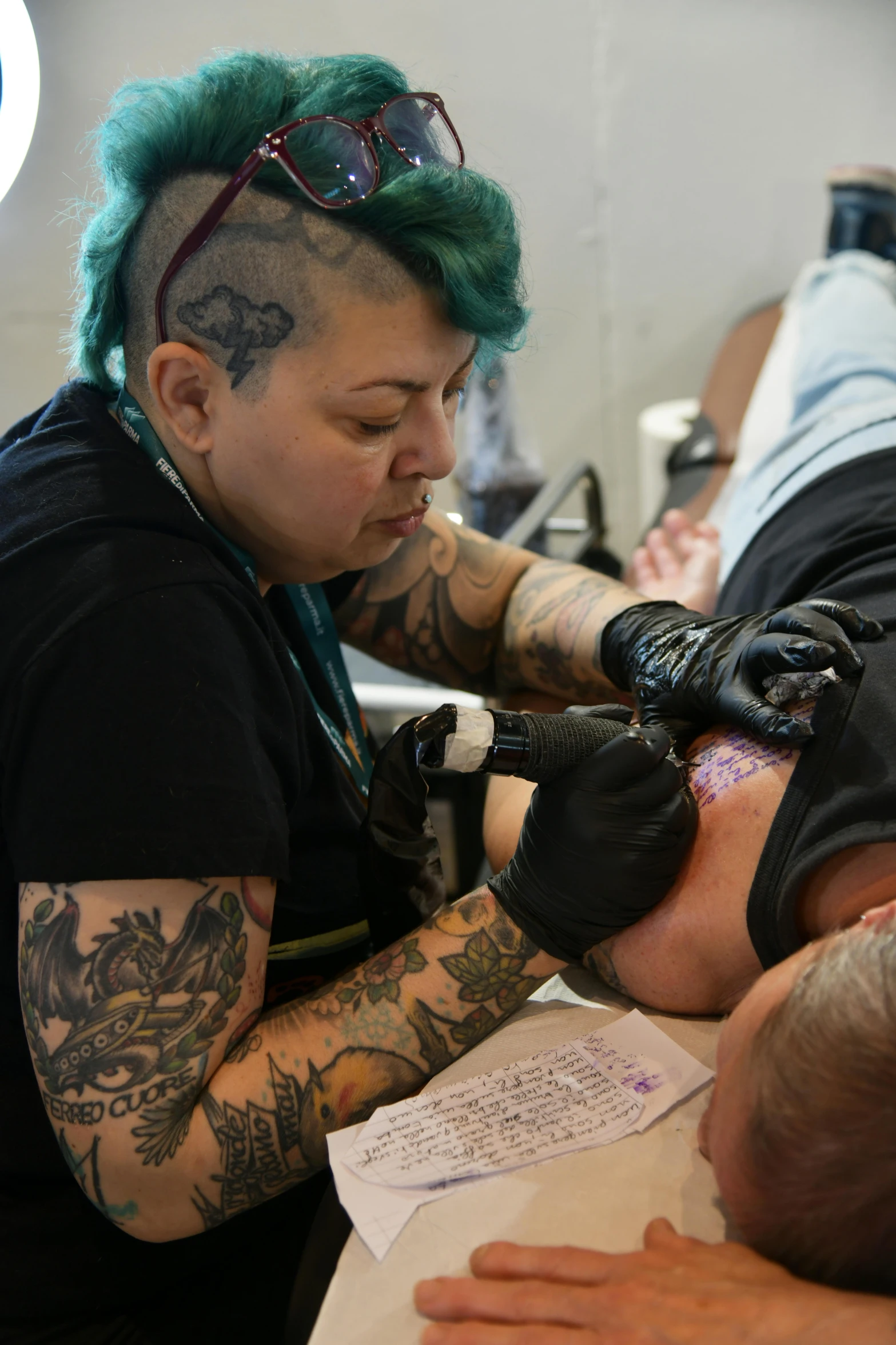 a man has green hair and a beard while he is getting tattoos