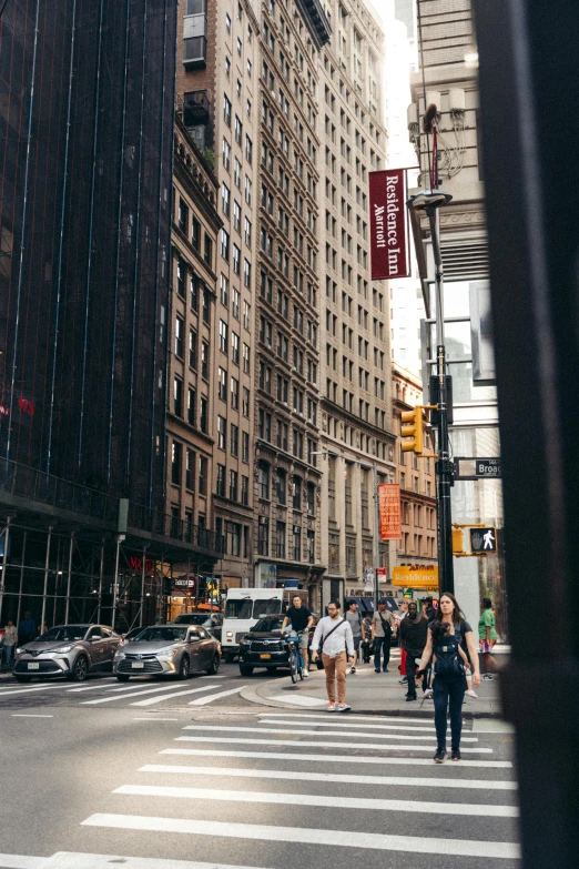 people walking across the street as cars pass on a busy road