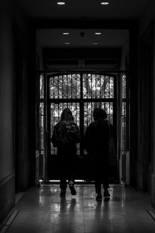 two women walk out the door of a building