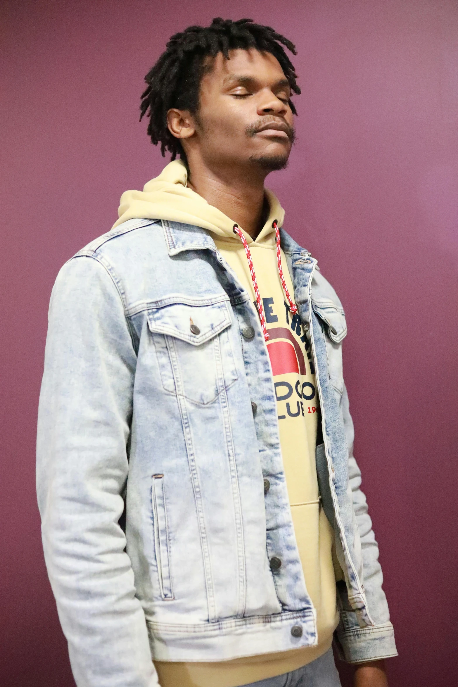 a man with dreadlocks standing next to a wall